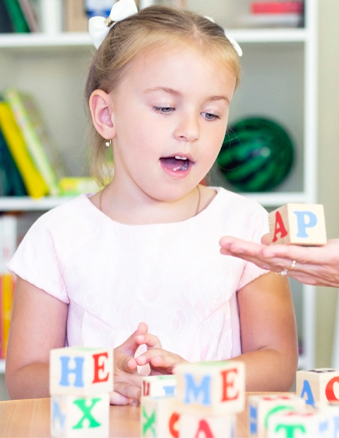 A young girl playing with alphabet blocks